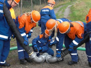 Kinder und Jugendliche der Jugendfeuerwehr kuppeln Geräte aneinander.