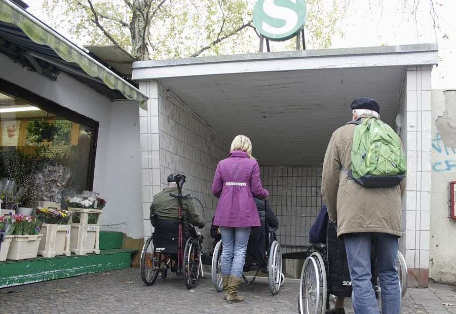 Menschen im Rollstuhl vor den Treppen zur Unterführung zum S-Bahnsteig in Eichwalde. (Foto: Jörg Levermann)