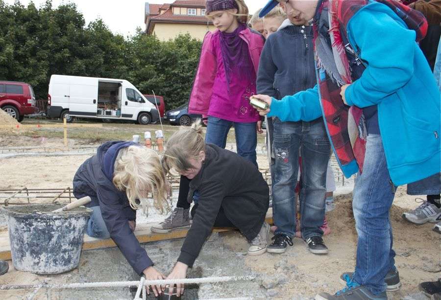 Schülerinnen und Schüler versenkten einen Stahlzylinder, gefüllt mit den Namenslisten der Schüler der Grundschule Villa Elisabeth, einer Tageszeitung, verschiedenen Münzen und weiteren Dokumenten im Grundstein des neuen Schulgebäudes. (Foto: Jörg Levermann)